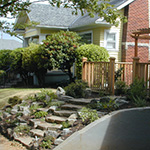 Natural stone placement makes a front slope more welcoming and accessible. Installation by Apogee Landscapes.