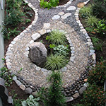 Colorful river rocks stand on end to activate reflexology points on the feet while you walk. Plants add to the therapeutic effect at Groundspring Healing Center. Hardscape by Emerald Stone Masonry.